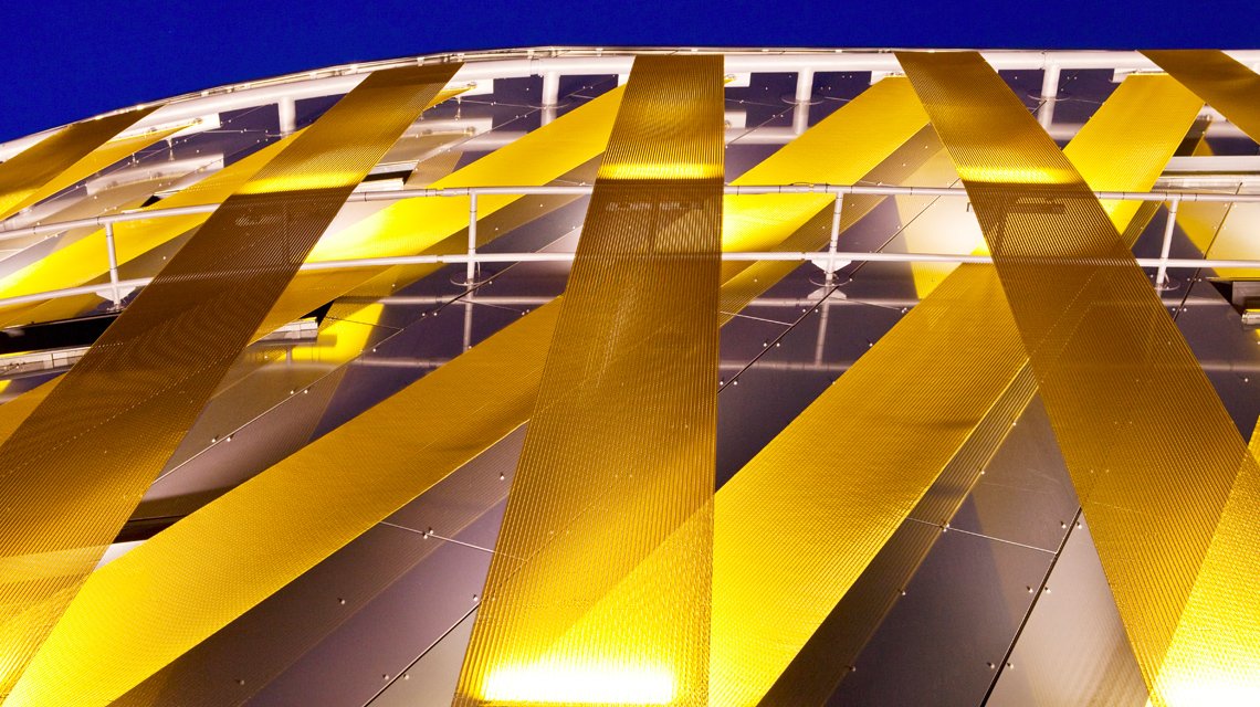 Bandes de maille métallique câblée colorée SATURNP05140 en façade architecture sur mesure www.maillemetaldesign.fr - <p>façade moderne d’un centre commerciale revêtue de bandeaux de maille métallique câblée. La maille métallique STAURN est composée de câbles inox et de tiges métallique inox recouvertes d’une couche de peinture plastifiée.</p>