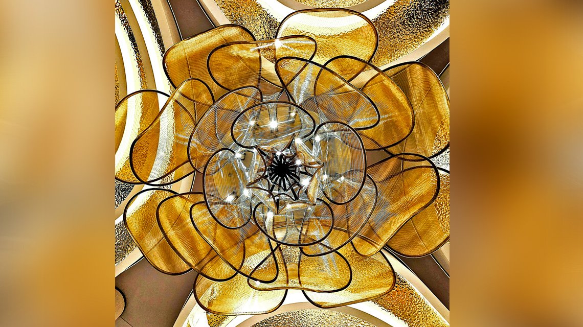 Vue centrale du chandelier en maille métallique - <p>Vue depuis le dessous du chandelier en maille métallique, révélant sa composition circulaire et les jeux de lumière créés par la structure métallique.</p>