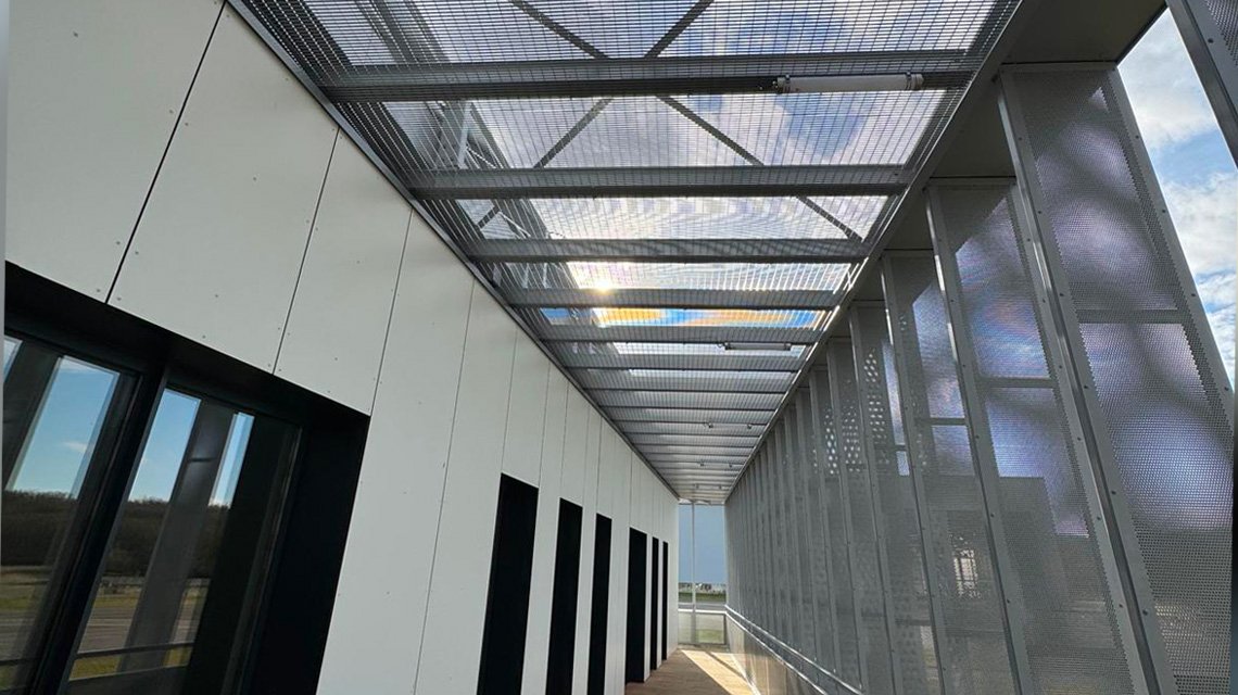 Pergola brise-soleil en grille Slot – Airbus Ziegler - <p>Pergola métallique équipée d’une grille électro-soudée type Slot Prozinal RAL 9006 mat, intégrée au Delivery Center Airbus Ziegler. Protection solaire et confort des circulations extérieures.</p>