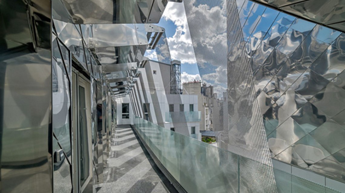 Maille métallique câblée inox en façade de logements à Paris  - <p>maille métallique câblée appelée SATURN fabriquée sur mesure en acier inoxydable 316L et mise en oeuvre en bandeaux, en panneaux zig zag sur la façade du bâtiment de logements. La maille métallique allie esthétique et fonctionnalité comme brise-soleil.</p>