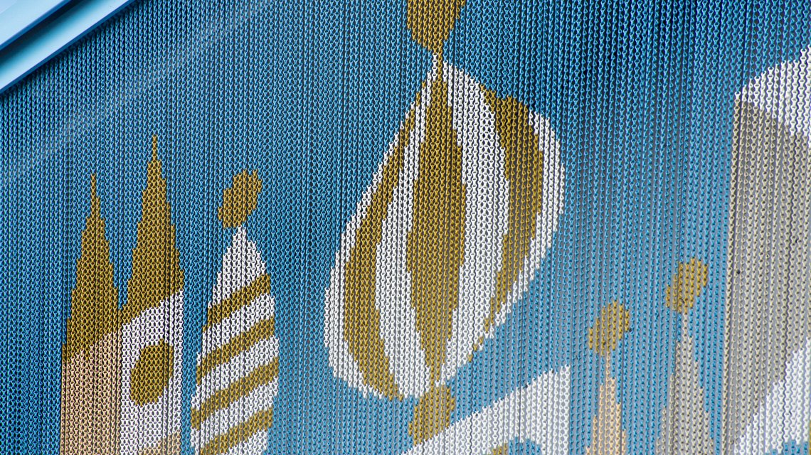 Gros plan dôme stylisé – Maillons aluminium Kriskadecor - <p>Détail d’un dôme stylisé reproduit en aluminium anodisé sur la façade décorative Kriskadecor du Disney Village. Le zoom montre le rendu précis du graphisme sur maillons.</p>